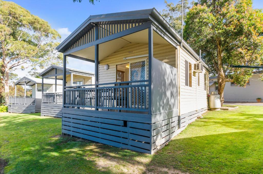 a small house with a blue deck on a yard at Mittagong Caravan Park in Mittagong