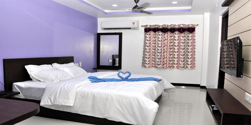 a bedroom with a bed with a blue bow on it at Sara Regency in Palni