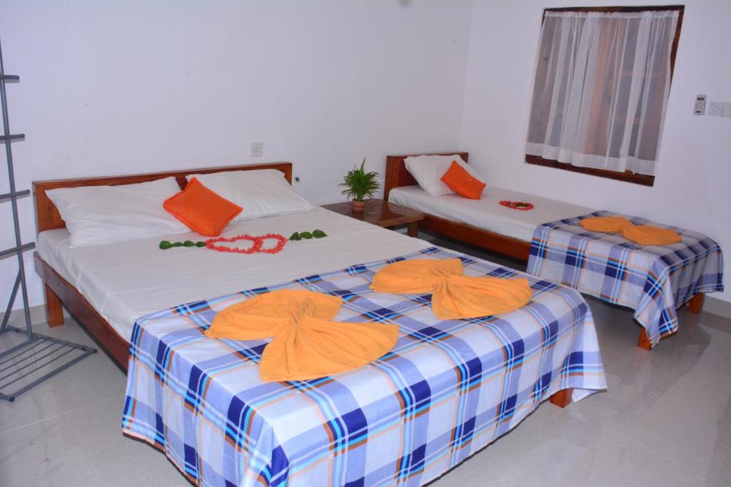 2 letti in una camera con asciugamani arancioni di Pleasant Park Holiday Inn a Trincomalee