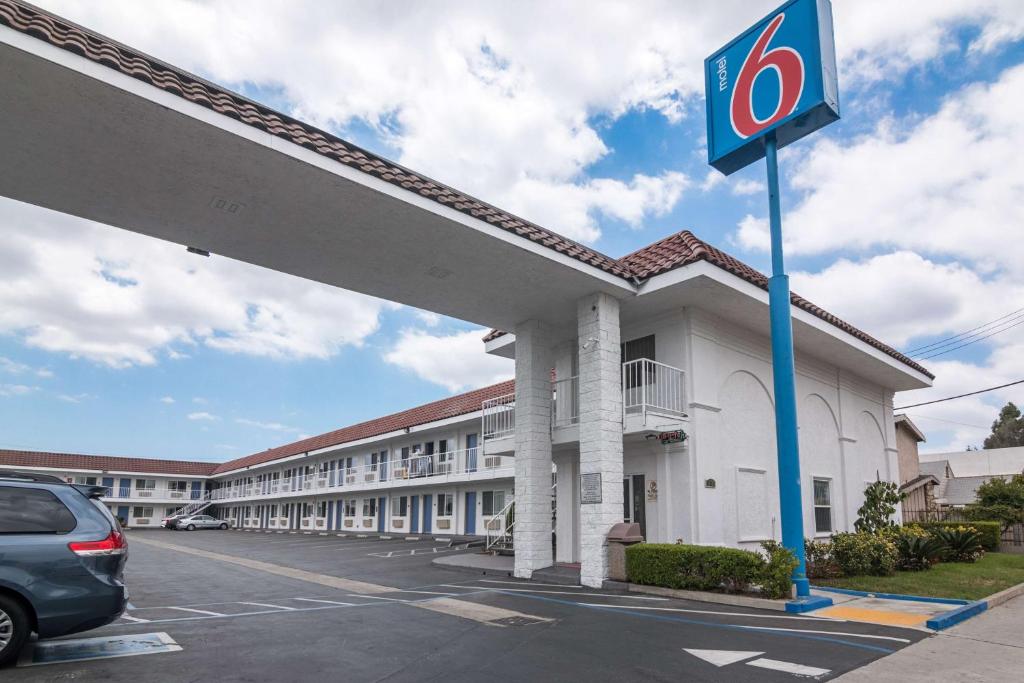 a hotel exterior with a car parked in a parking lot at Motel 6-Norwalk, CA in Norwalk