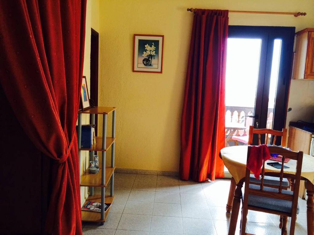 a room with red curtains and a table and a window at Finca Santa Catalina in Hermigua