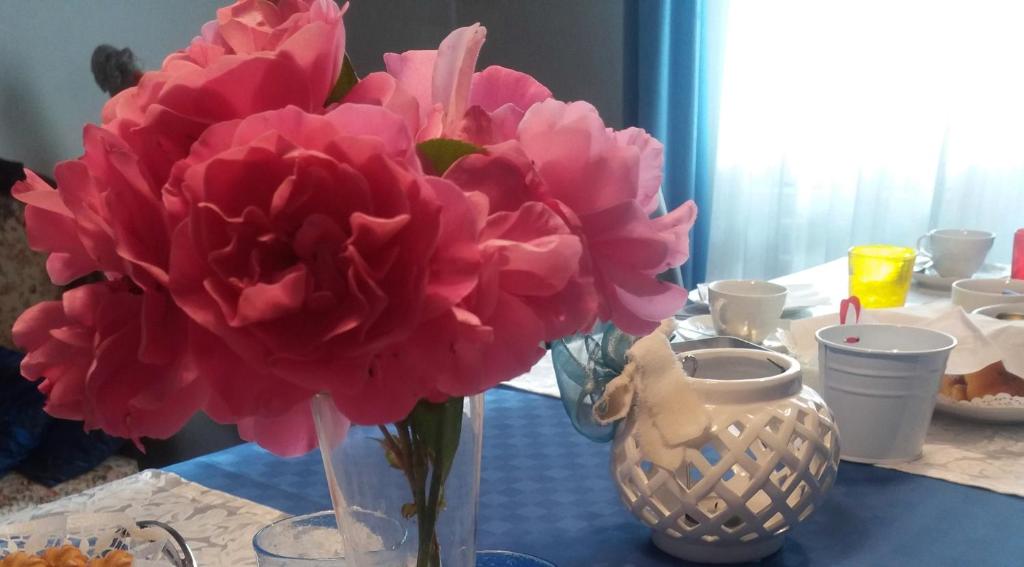 un jarrón con flores rosas en una mesa en B&B Smile, en Fiorano Modenese