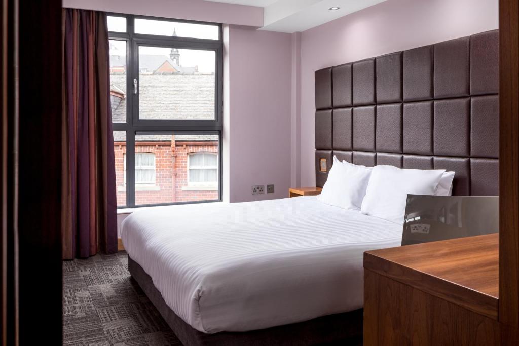 a hotel room with a large bed and a large window at Roomzzz Leeds City in Leeds
