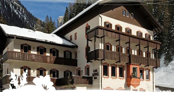 a large building with snow on top of it at Hotel Alpino Plan in Selva di Val Gardena