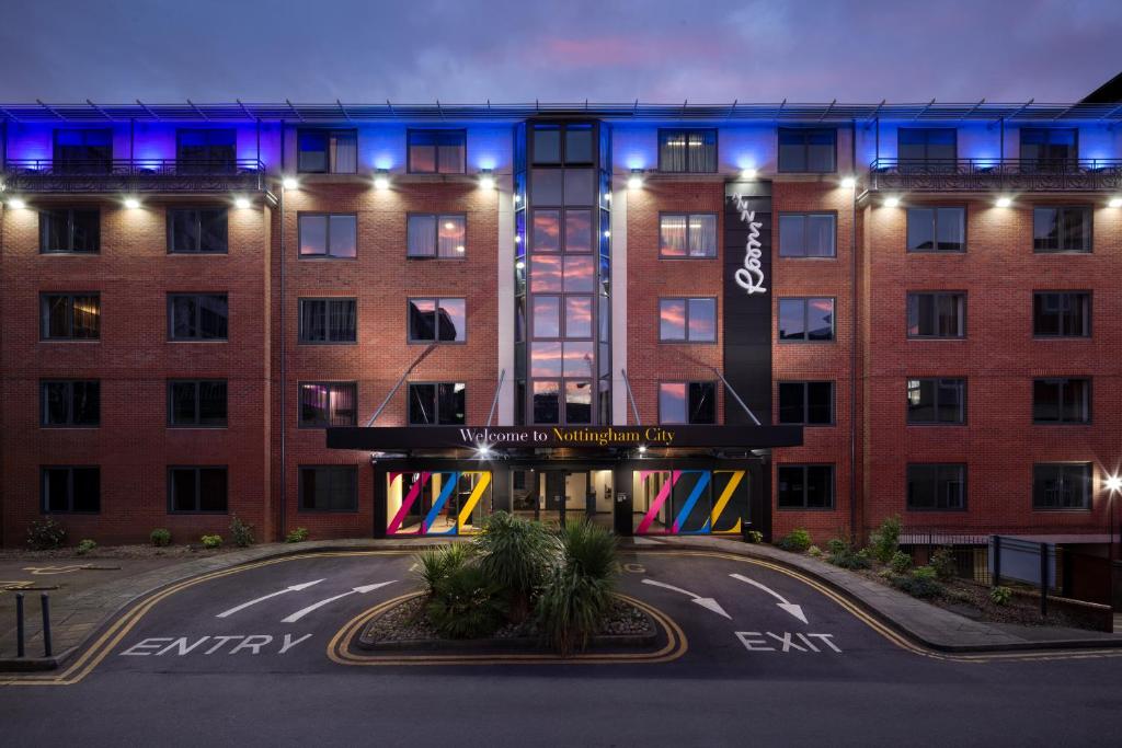 un edificio con una fachada iluminada por la noche en Roomzzz Nottingham City, en Nottingham