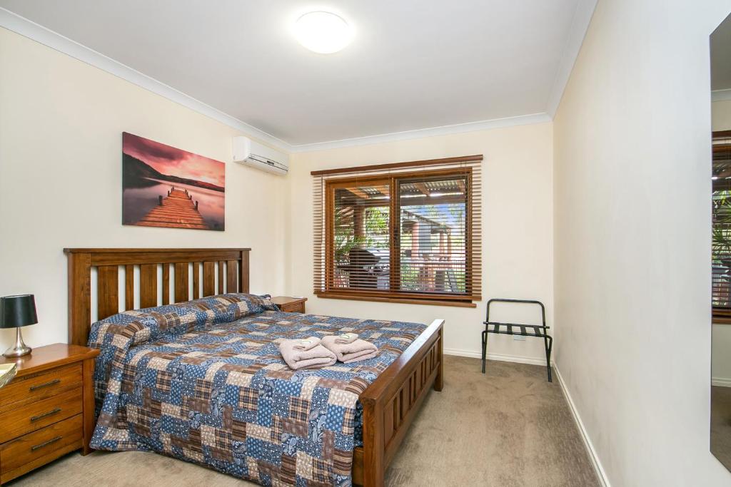 a bedroom with a bed and a desk and a window at Coranda Lodge in Armadale