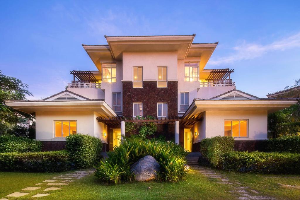 une grande maison blanche avec un jardin en face de celle-ci dans l'établissement La Floret Villas Yalong Bay Sanya, à Sanya