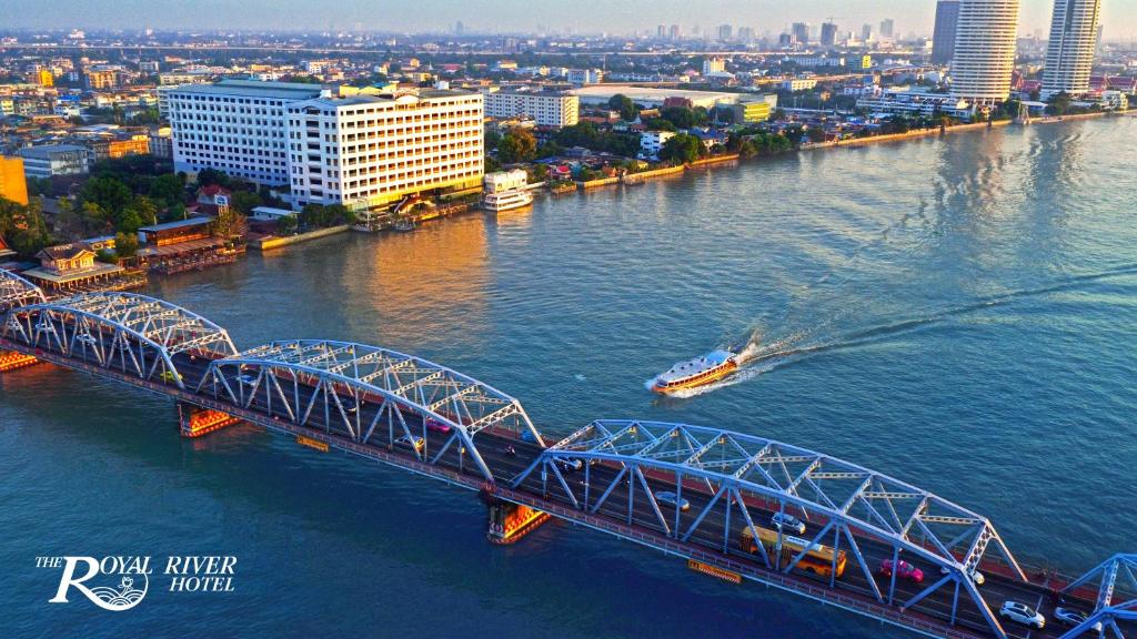a bridge over a river with a boat at The Royal River Hotel in Bangkok
