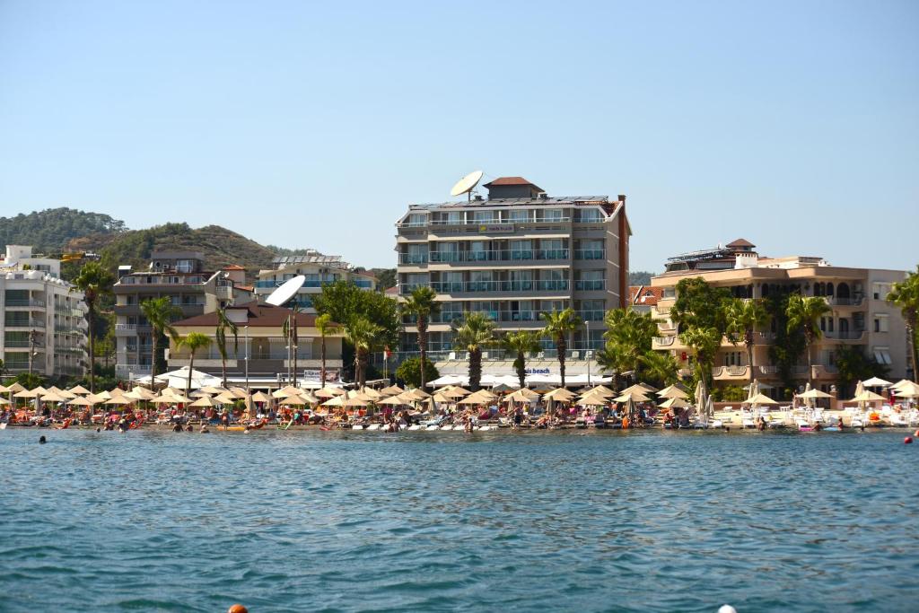 una playa con sombrillas y gente en la playa en Maris Beach Hotel, en Marmaris