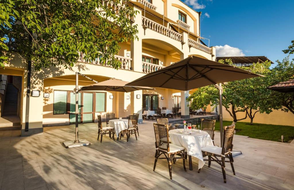 an outdoor patio with tables and chairs and umbrellas at Arève Résidence Boutique Hotel in Yerevan