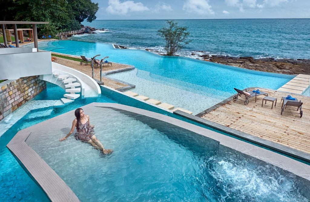 a woman in a swimming pool next to the ocean at Independence Hotel Resort & Spa in Sihanoukville