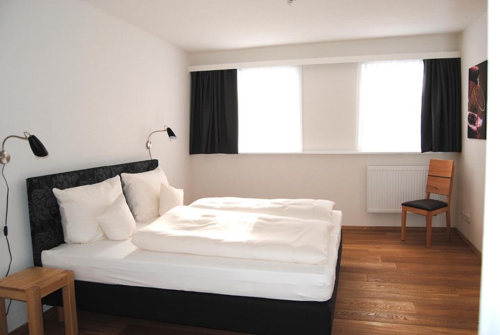 1 dormitorio con 1 cama blanca y 1 silla en FEWO am Weinmarkt, en Bad Windsheim