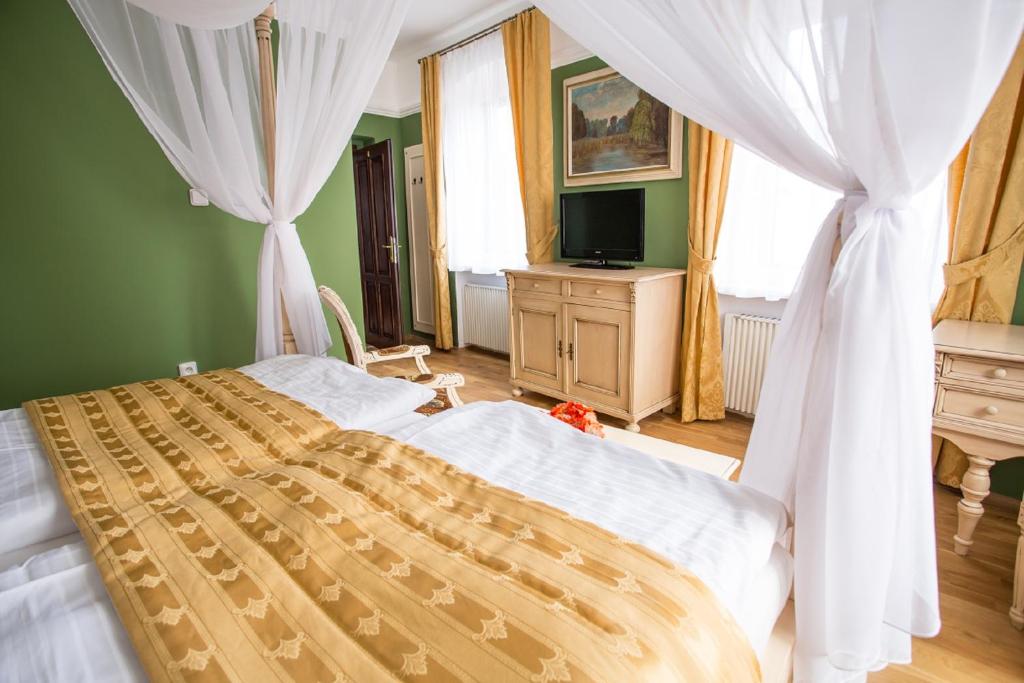 1 dormitorio con 1 cama con cortinas blancas y TV en Pension PREMIUM en Český Krumlov
