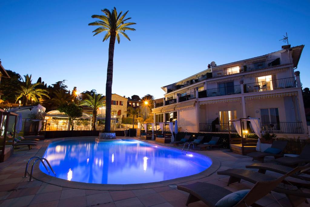 a swimming pool with a palm tree in front of a building at Boutique Hotel & Spa la Villa Cap Ferrat in Saint-Jean-Cap-Ferrat