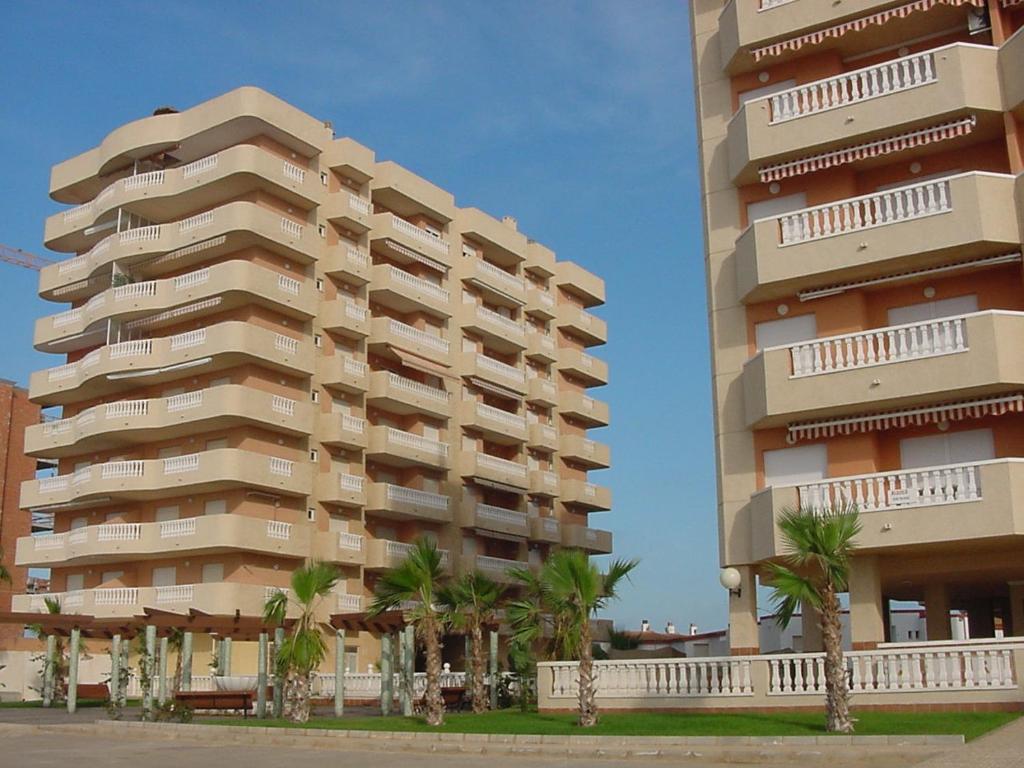 a large apartment building with palm trees in front of it at Apartamento Isla Grosa La Manga V.v. in La Manga del Mar Menor
