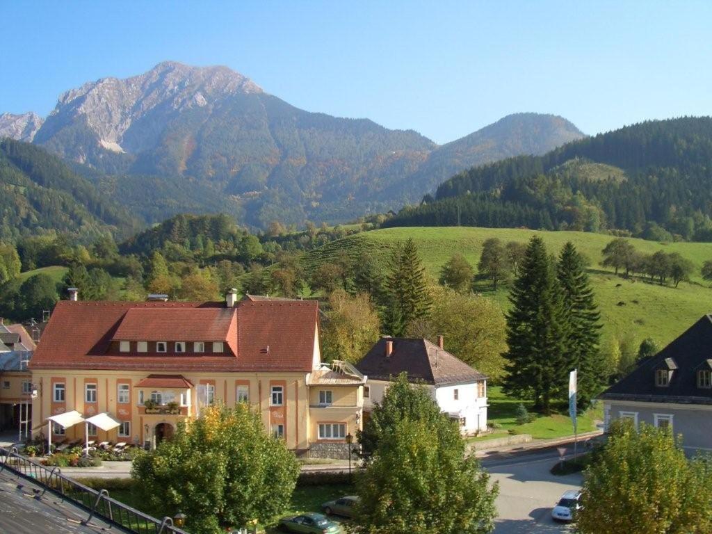 a house in a village with mountains in the background at Gästehaus zur Post - Heritage Inn in Spital am Pyhrn