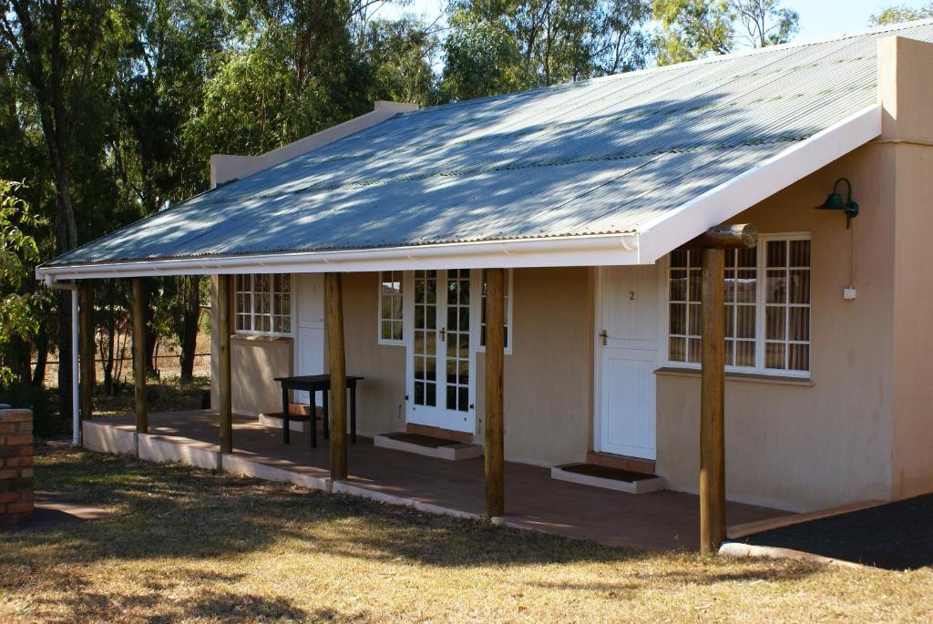 a small white house with a tin roof at Hluhluwe Country cottages in Hluhluwe