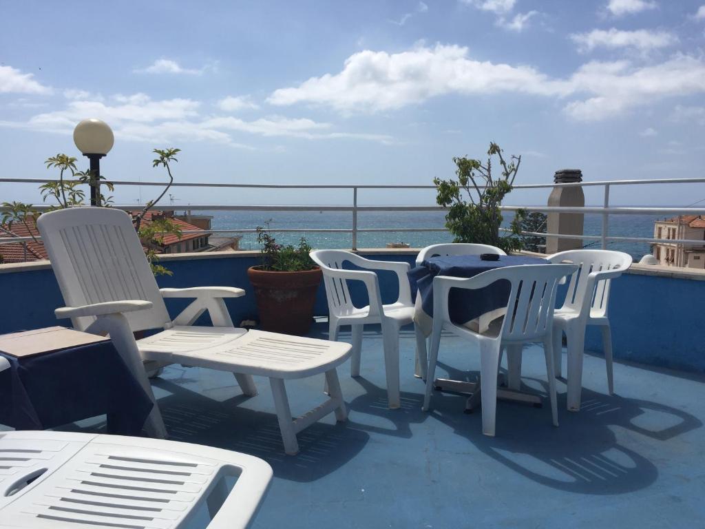 eine Gruppe weißer Stühle und Tische auf einem Balkon in der Unterkunft Hotel Belvedere in Sanremo