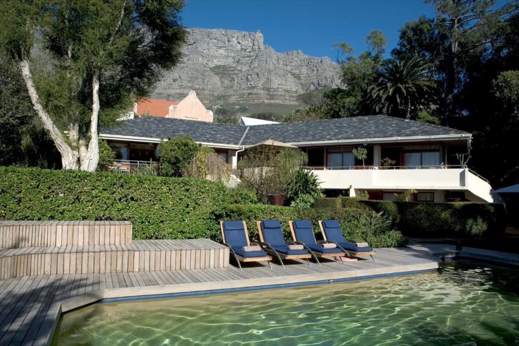 a house with lounge chairs and a swimming pool at Lézard Bleu Guest House in Cape Town