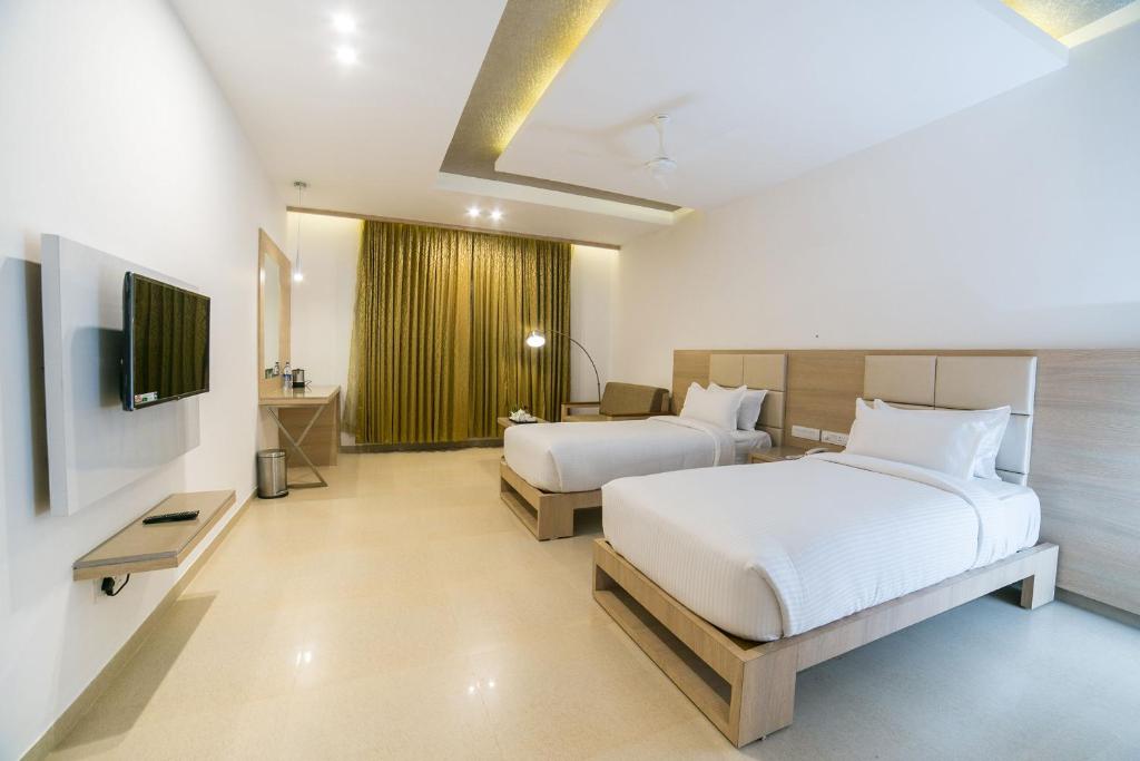 um quarto de hotel com duas camas e uma televisão em Hotel Vivera Grande em Dindigul