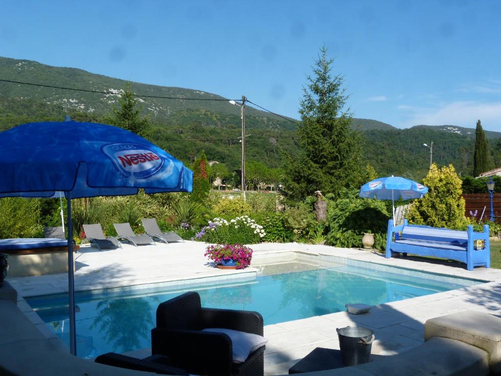 una piscina con sillas y sombrilla en Les Bambous B&B en Levens