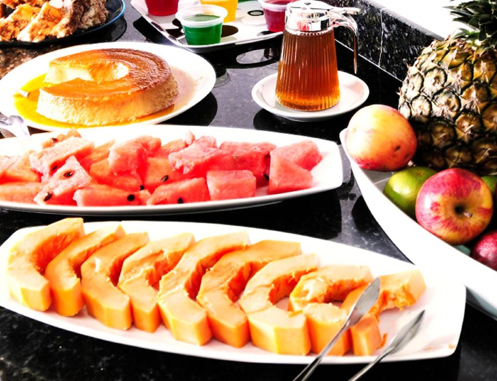 a table topped with plates of fruit and cakes at Grande Hotel Araçatuba in Araçatuba