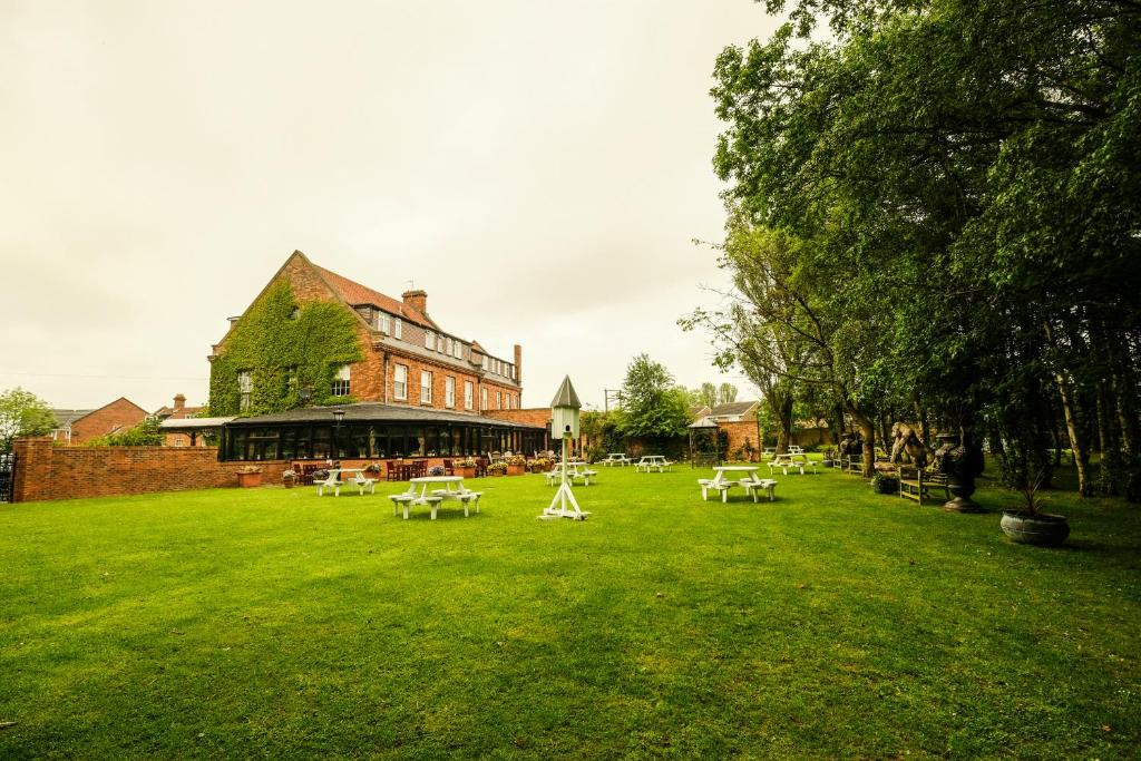 un ampio cortile verde con tavoli e un edificio di Bowburn Hall Hotel a Durham