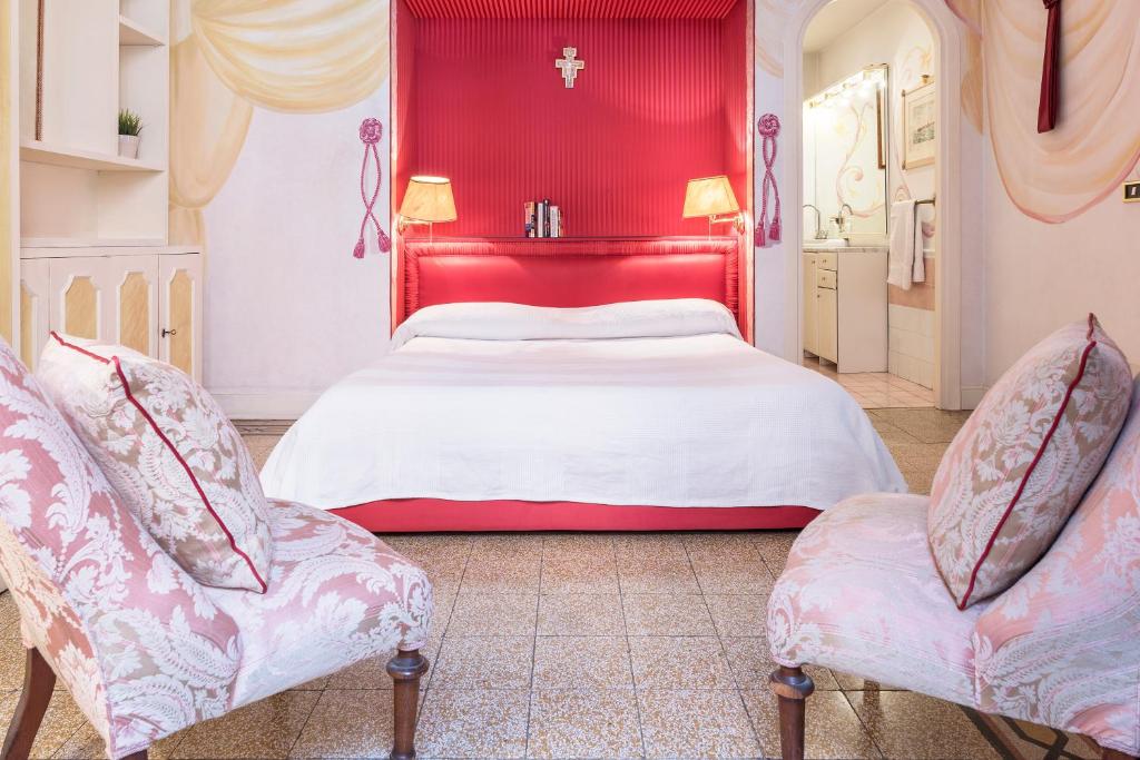 ローマにあるPiazza Colonna Apartment - Charme Homesの赤いベッドルーム(ベッド1台、椅子2脚付)