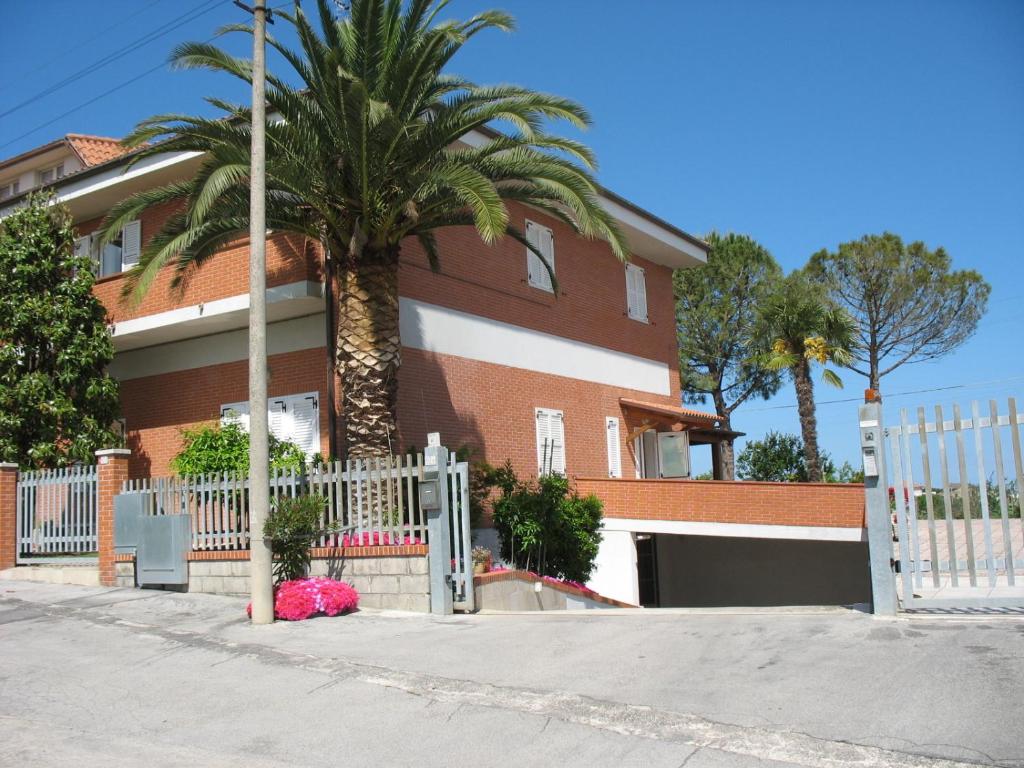 a palm tree in front of a house with a white fence at Bed & Breakfast Bompadre in Civitanova Marche