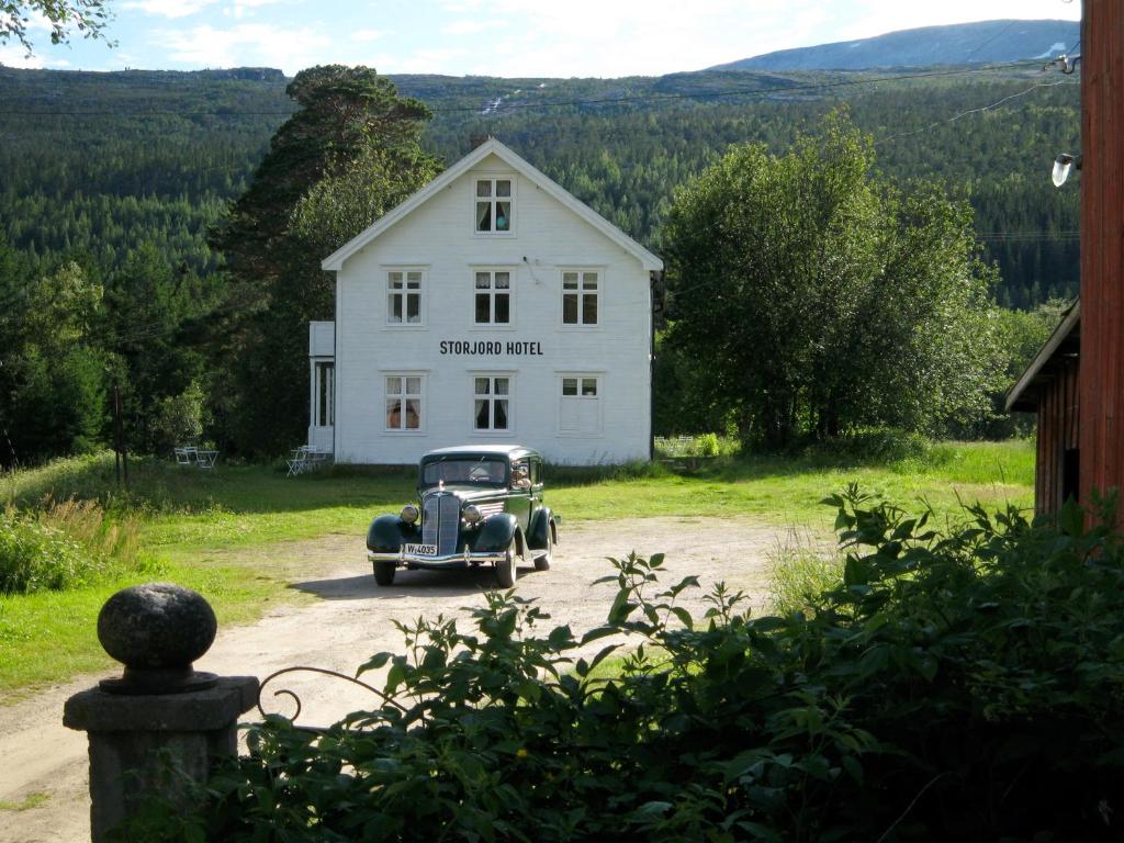 an old car parked in front of a white house at Storjord Hotel in Storjord