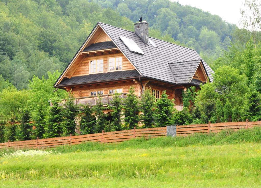 Cabaña de madera con techo negro y valla de madera en Krolowo Apartment, en Krościenko nad Dunajcem