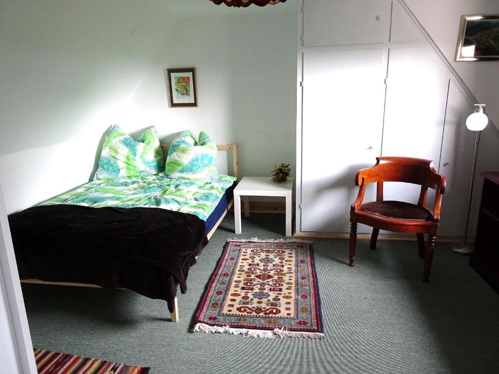 ein Schlafzimmer mit einem Bett, einem Stuhl und einem Teppich in der Unterkunft Haus Fermate in Wilhelmsfeld