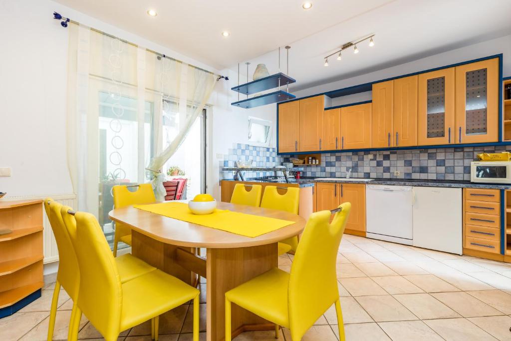 kuchnia z drewnianym stołem i żółtymi krzesłami w obiekcie Villa Tomić Apartment Mia near the sea w mieście Opatija