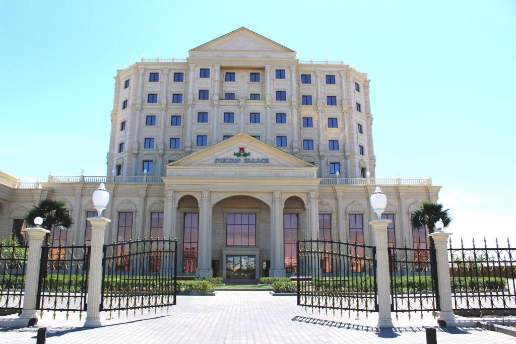 a building with a fence in front of it at Sultan Palace Hotel in Atyraū
