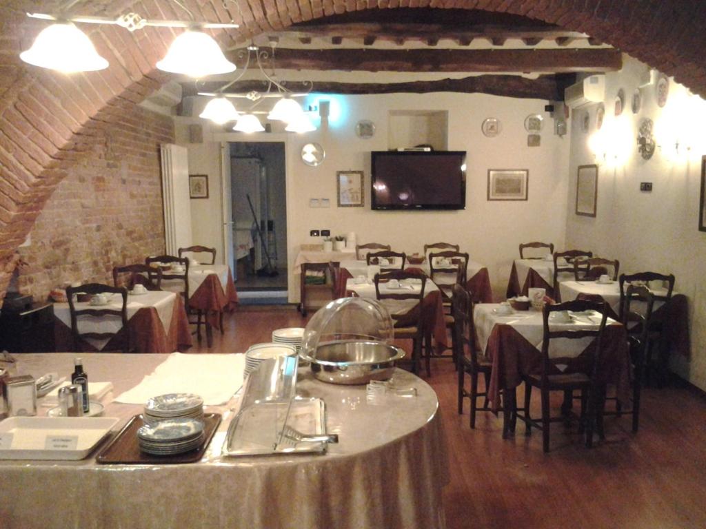 a dining room with tables and chairs and a television at Hotel Di Stefano in Pisa