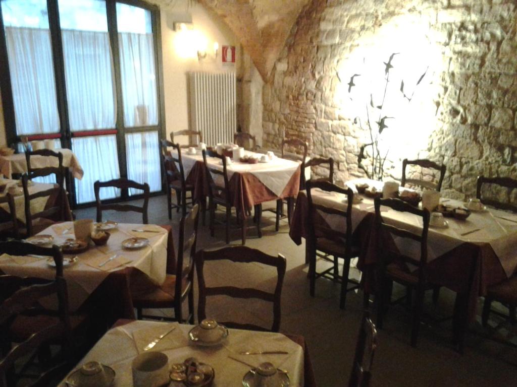 a dining room with tables and chairs and a stone wall at Hotel Di Stefano in Pisa