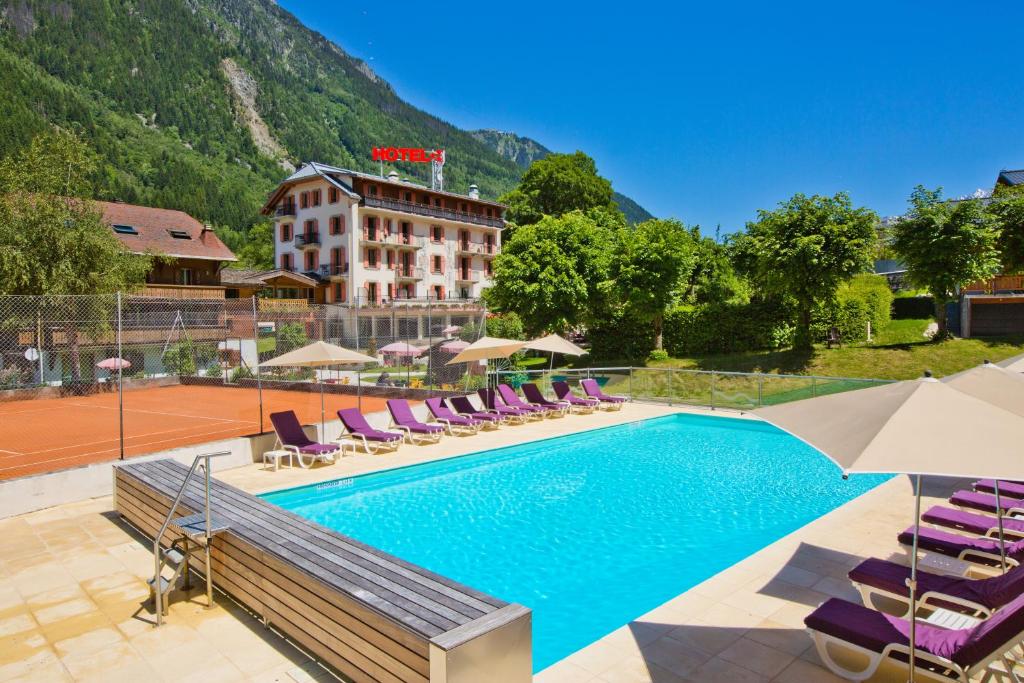 a swimming pool with lounge chairs and a hotel at Aiguille du Midi - H&ocirc;tel & Restaurant in Chamonix-Mont-Blanc