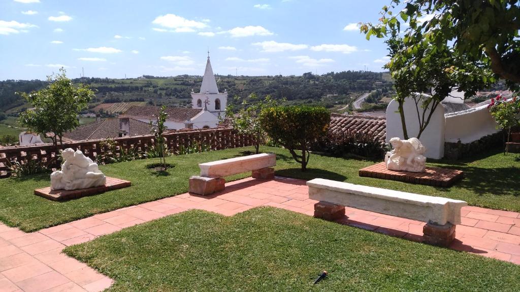 a group of park benches in front of a church at Casa da Talhada - Stone House in Óbidos