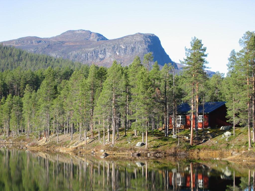 una cabaña en una colina junto a un lago en Årrenjarka Mountain Lodge en Kvikkjokk