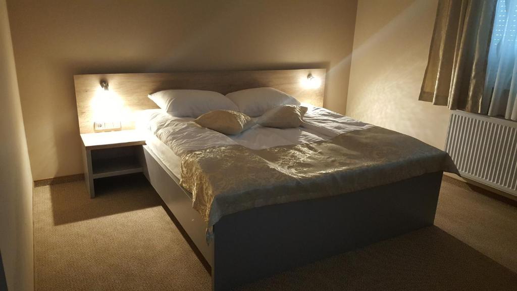 a bed with two pillows and a night stand in a bedroom at Rooms Comfor in Bihać