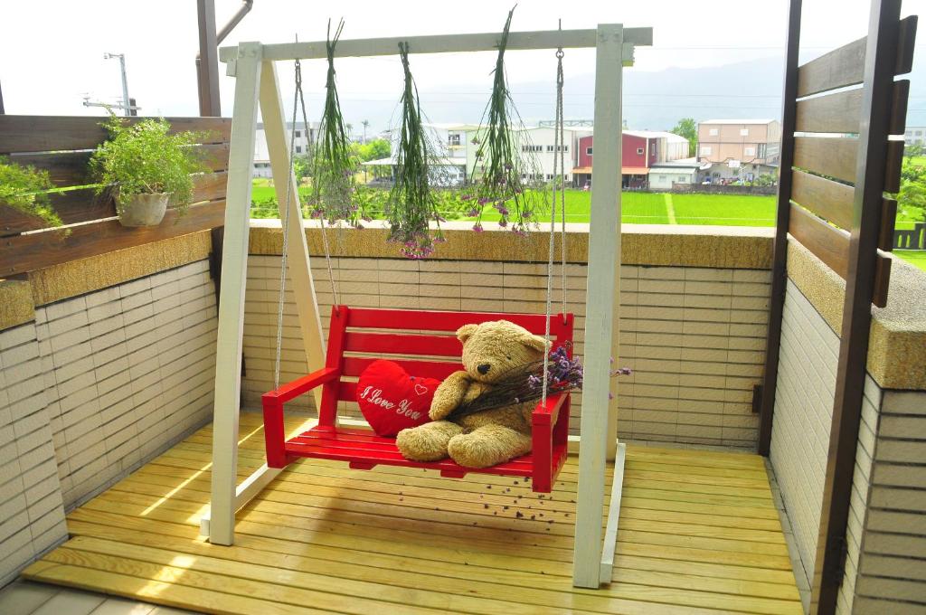 a teddy bear sitting on a swing on a balcony at Happy Orange Homestay in Dongshan