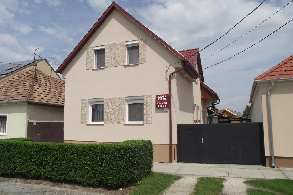 a white house with a gate in front of it at Radek Vendégház és Apartman in Halászi