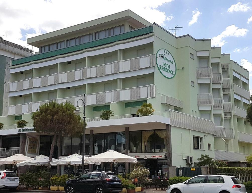 a large building with cars parked in front of it at Hotel Residence Adriana in Cesenatico