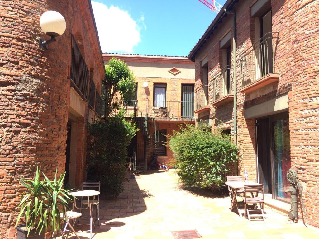 einen Innenhof mit Tischen und Stühlen in einem Gebäude in der Unterkunft Le Duplex in Toulouse