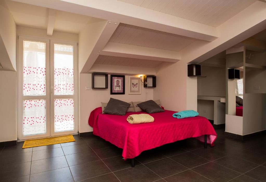 un letto rosso in una stanza con una grande finestra di B&B Casa Liuzza a Santa Teresa di Riva