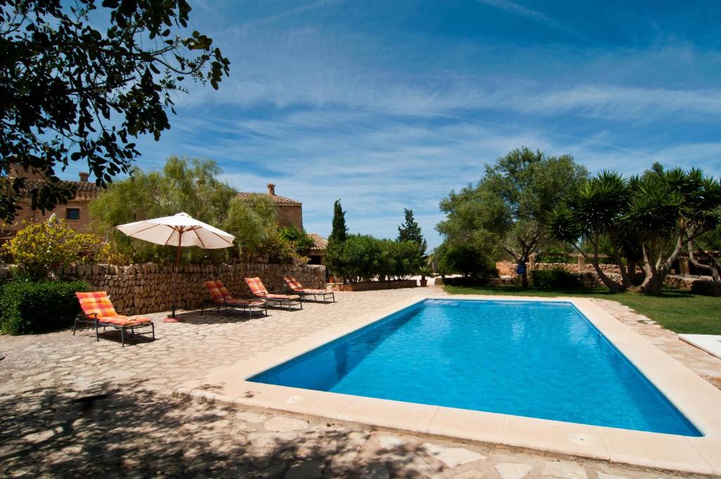 una piscina con sillas y sombrilla en Es Rafal Roig (Blau), en Manacor