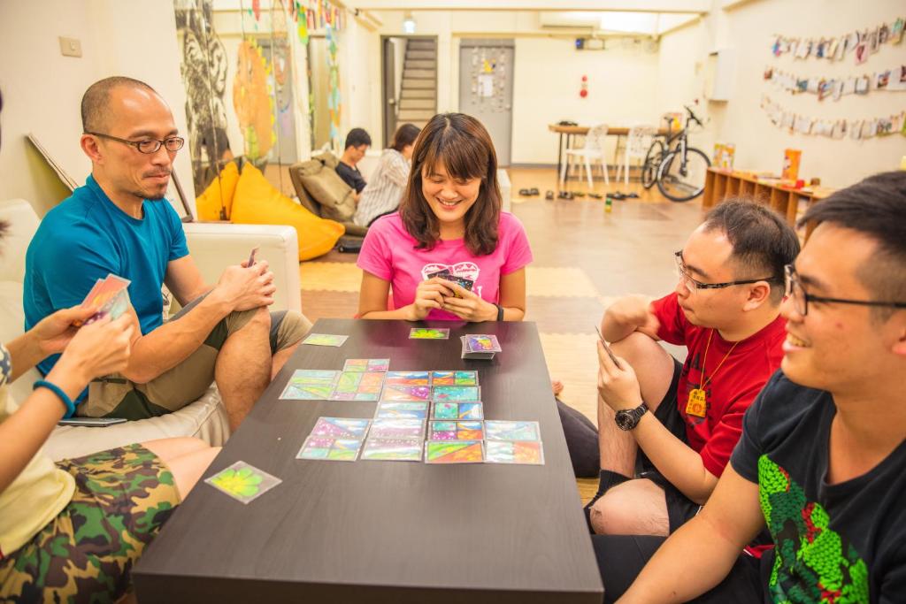 a group of people sitting around a table playing a game at On My Way - Taipei Hostel in Taipei