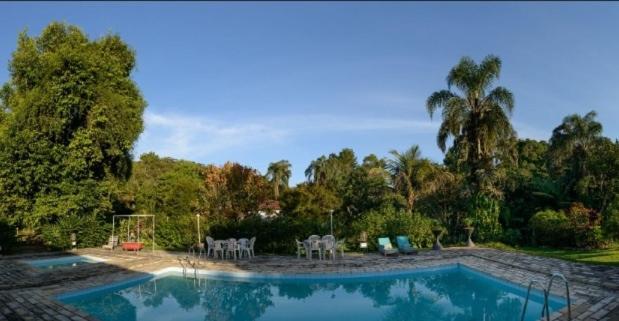 una piscina con mesas y sillas en un patio en Hospedaria Abbud & Fernandez, en Ipiabas