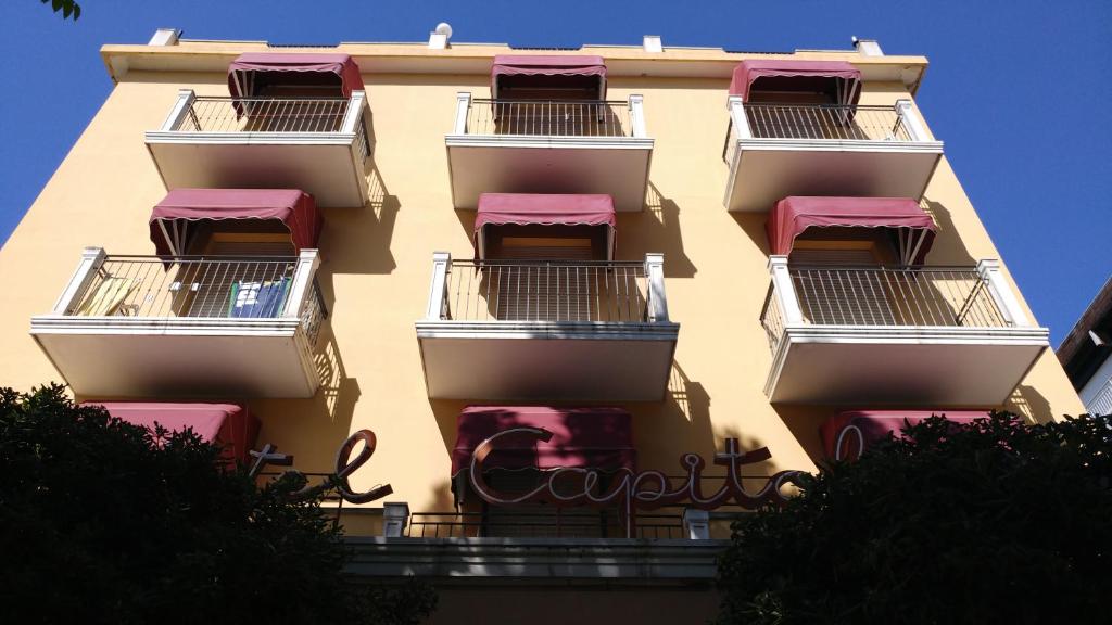 un grand bâtiment avec balcon et toits roses dans l'établissement Hotel Capitol, à Rimini