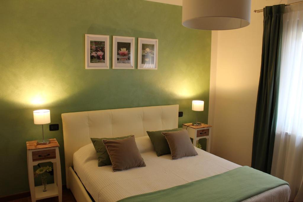 a bedroom with a bed with green walls and two lamps at Casa "La Valle dei Segni" in Piancogno